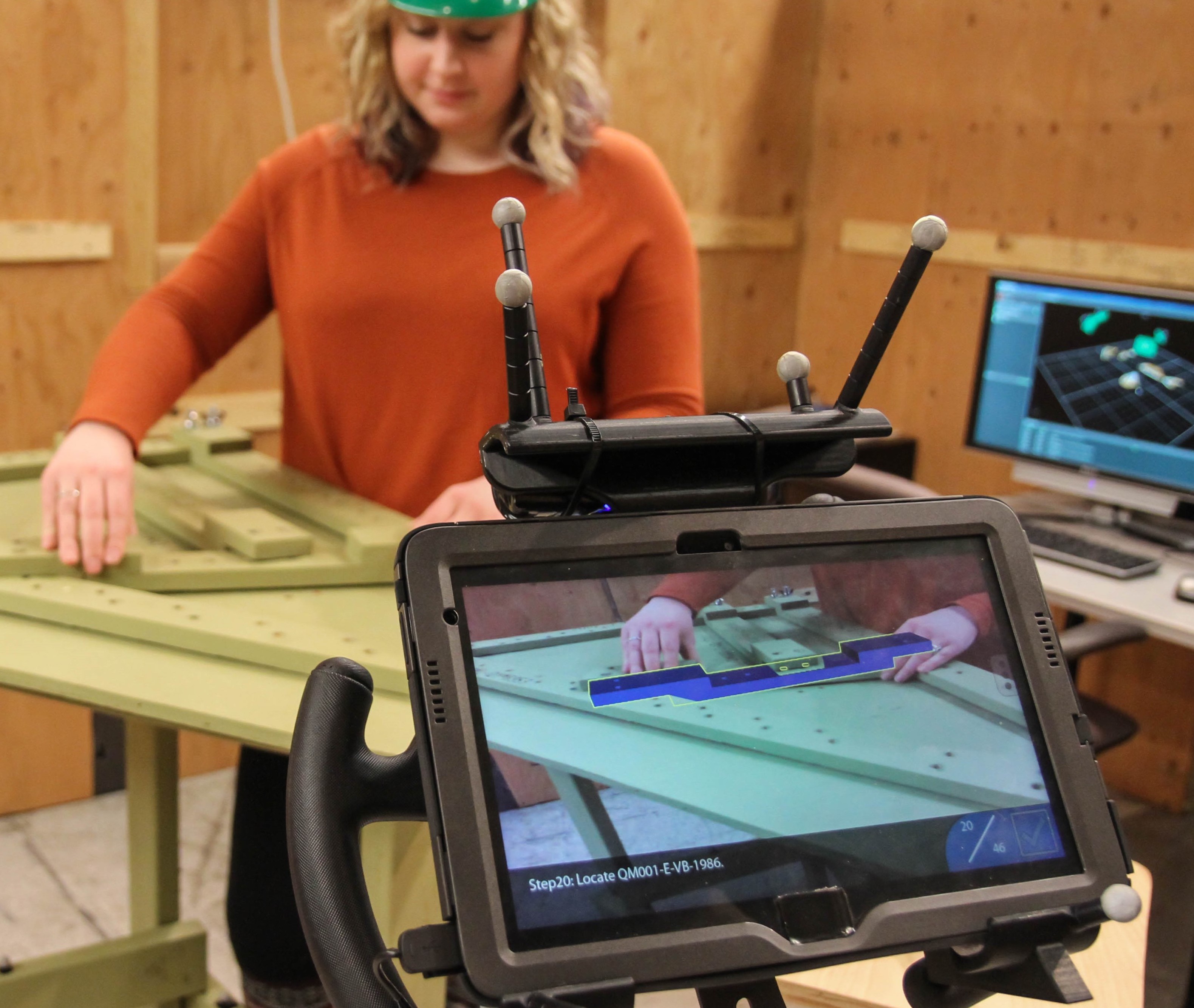 Woman performing assembly task using AR tablet.